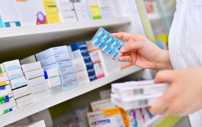 Pharmacist selecting boxed medicines from a shelf